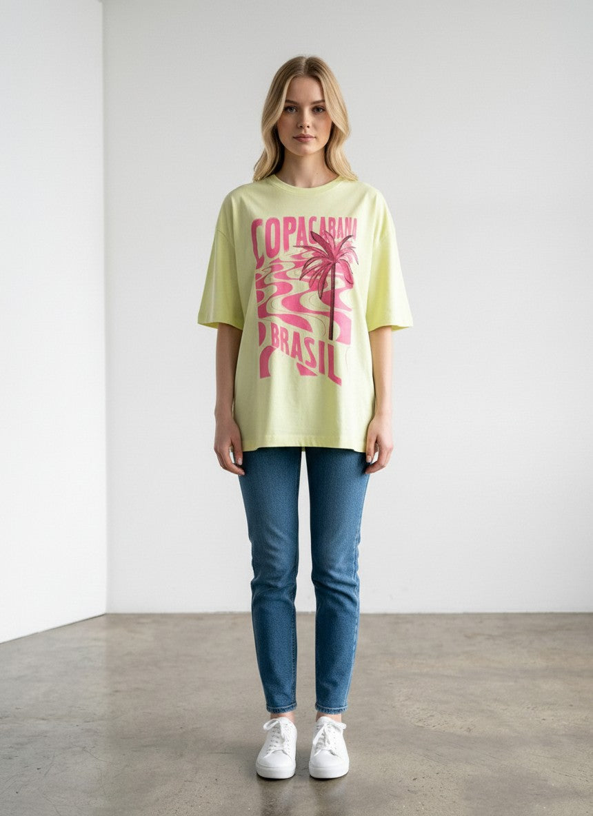 Modelo veste camiseta Aoi Closet Farm Rio amarela neon oversized com estampa rosa Copacabana Brasil em algodão.